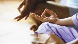 Three people meditating in yoga class, side view, low section